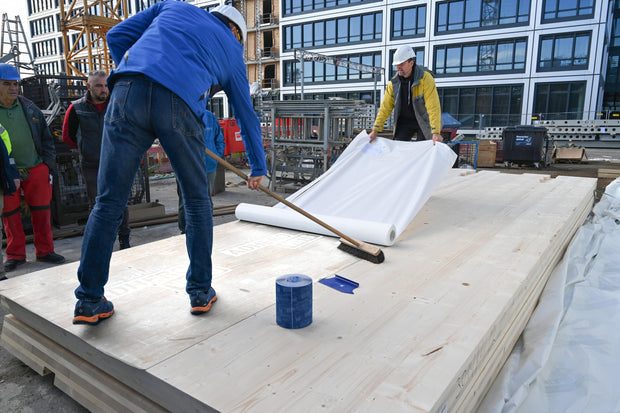 Pro Clima SOLITEX ADHERO VISTO öntapadó fólia simítása seprűvel CLT panelen: a légzáró réteg buborékmentes, szakszerű rögzítése.